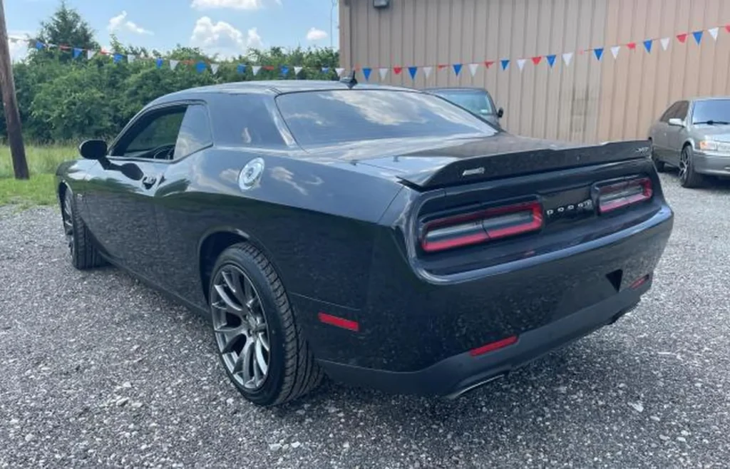 Tył Dodge Challenger – ujęcie 3/4 z prawej, szeroki spoiler, poziome lampy LED, emblemat SRT, sportowe koła.