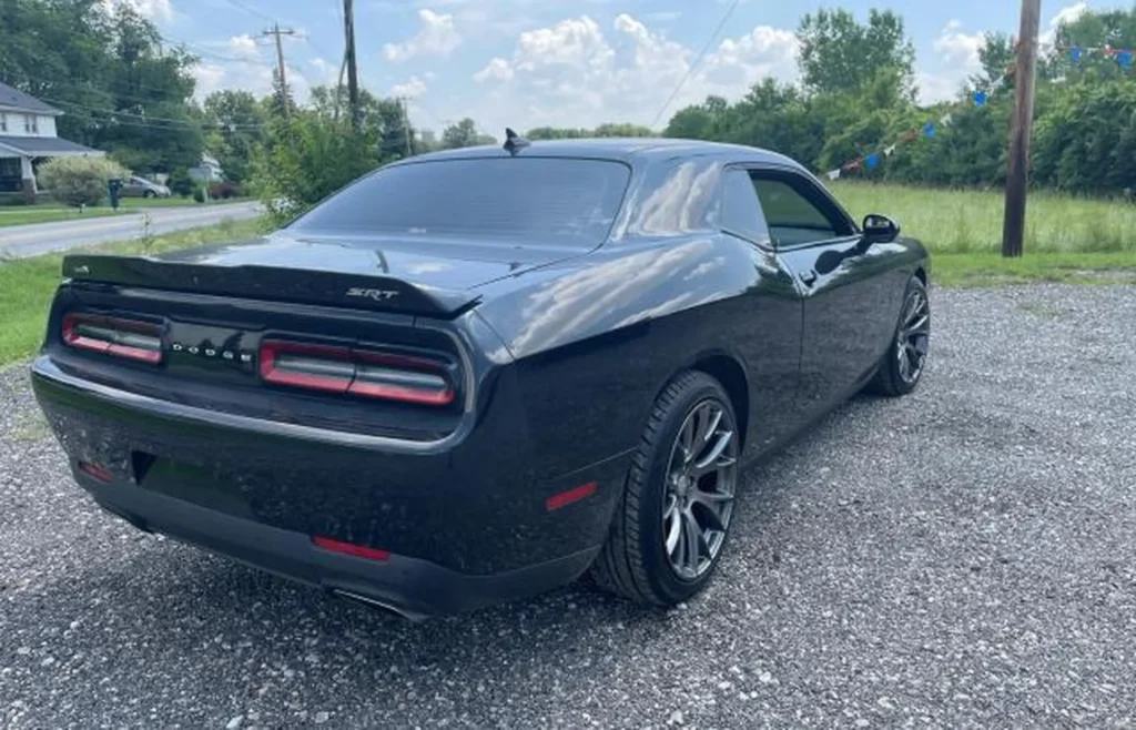 Tył Dodge Challenger – ujęcie 3/4 z lewej, logo DODGE, podwójne końcówki wydechu, przyciemnione szyby.