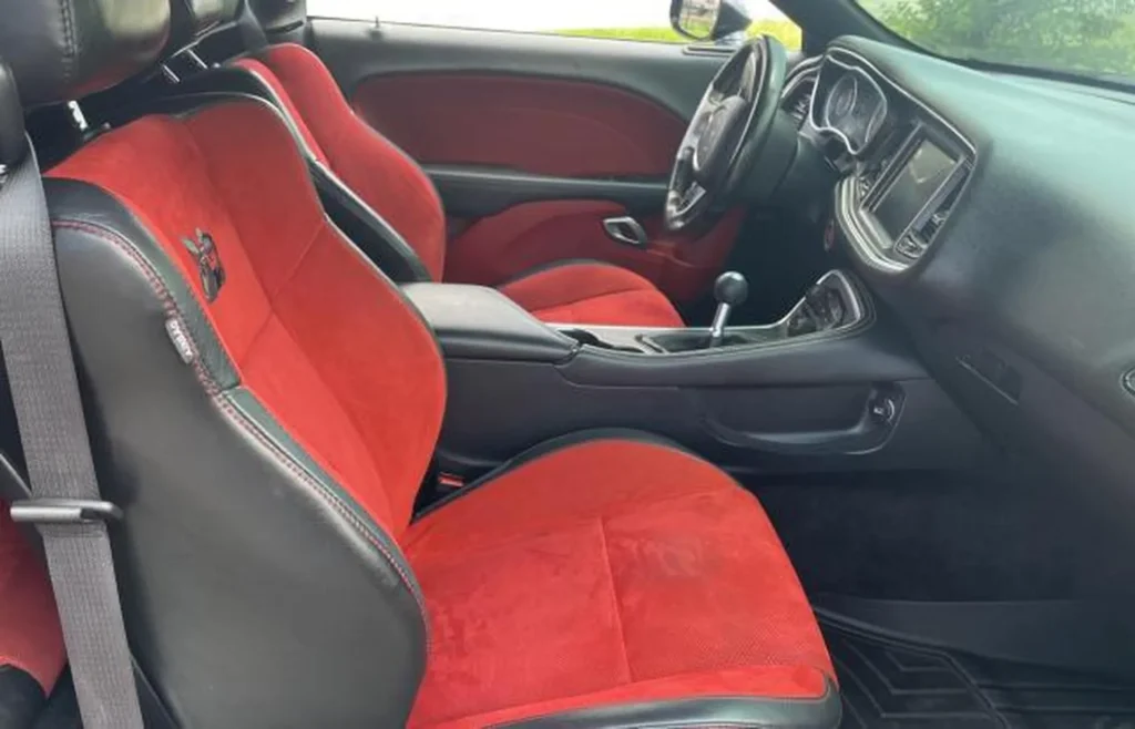 Wnętrze Dodge Challenger – czerwono-czarne fotele SRT, ręczna skrzynia biegów, sportowa kabina.