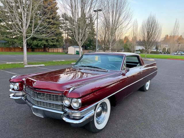 Bordowy Cadillac z lat 60. z przodu z lewej, białe opony i dużo chromu.