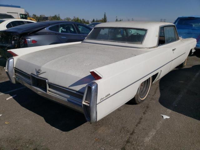 Biały Cadillac coupe od tyłu, zakurzone nadwozie, widoczne płetwy.