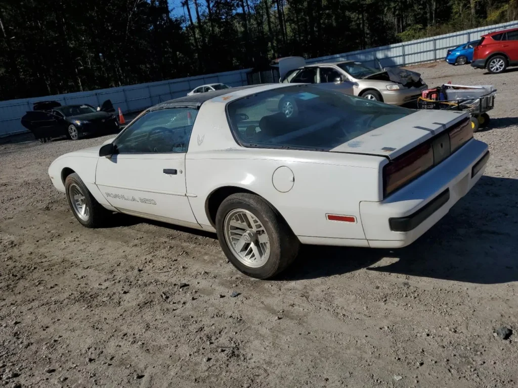 Tylny lewy róg Pontiaca Firebird Formula 350 – profil auta na żwirze, stan do renowacji.