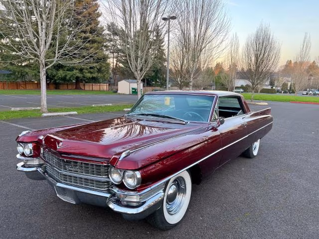 Bordowy Cadillac z lat 60. z przodu z lewej, białe opony i dużo chromu.