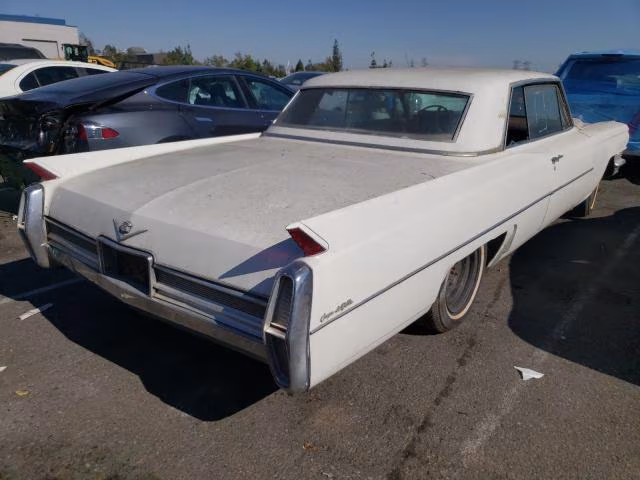 Biały Cadillac coupe od tyłu, zakurzone nadwozie, widoczne płetwy.