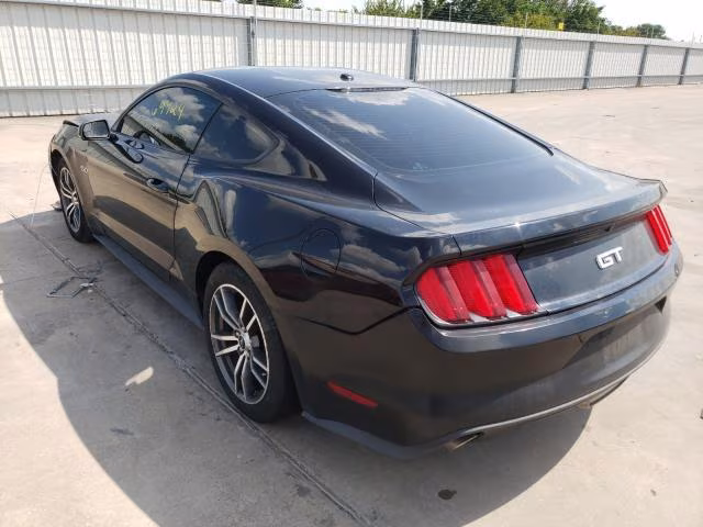 Czarny Ford Mustang GT, tył-lewy rzut, zaparkowany na betonie, seryjne felgi.