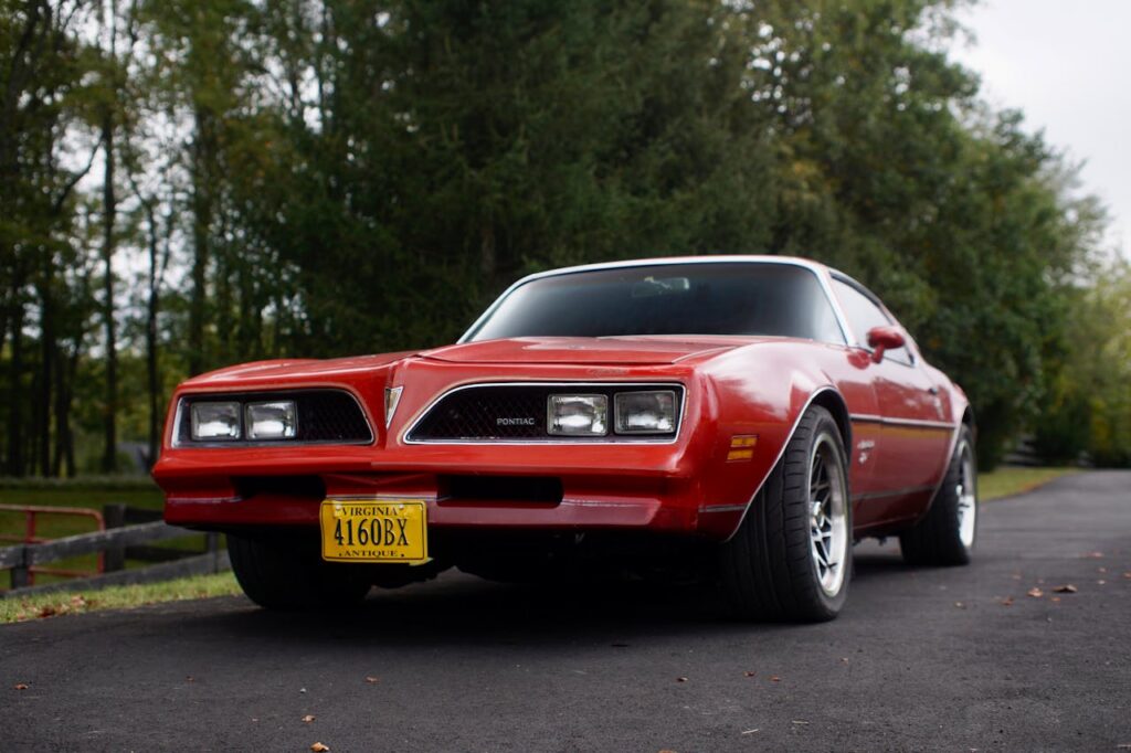 Czerwony Pontiac Firebird drugiej generacji (1977–1978) z żółtą tablicą z Wirginii, zaparkowany na leśnej drodze