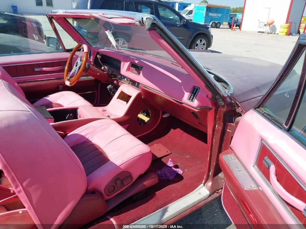 Wnętrze kabrioletu – różowe fotele i kokpit, brak części konsoli, drewniana kierownica.