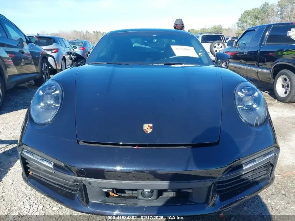 Przód Porsche 911 Turbo S – frontalne ujęcie z herbem Porsche na masce; uszkodzony dolny grill/zderzak.
