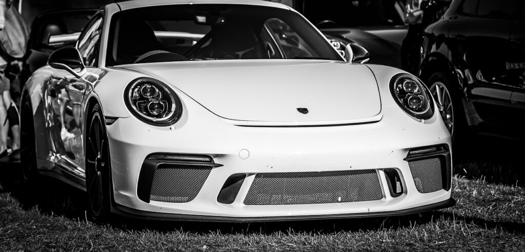 Białe Porsche 911 uchwycone na czarno-białej fotografii, z agresywnym przodem, dużymi wlotami powietrza i sportowym charakterem.