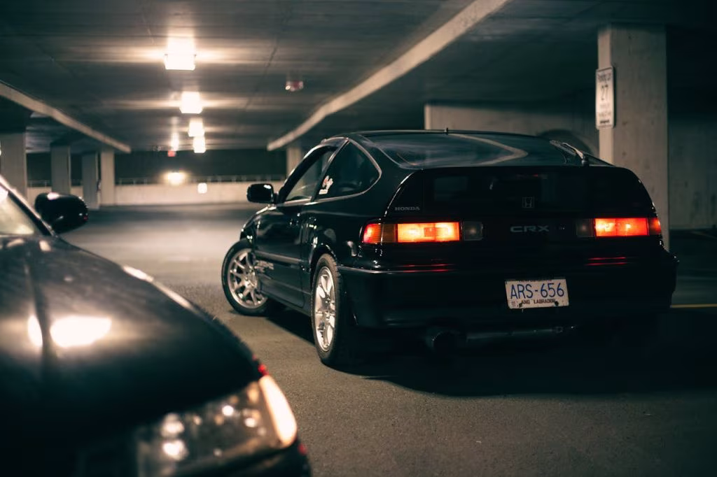 Czarna Honda CRX z włączonymi tylnymi światłami w podziemnym parkingu nocą