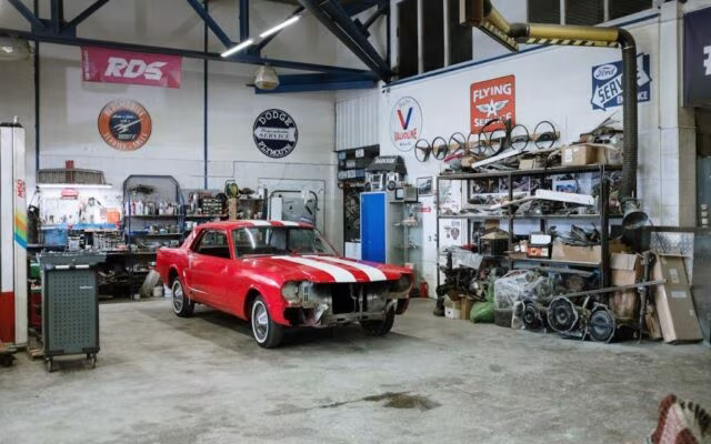 Czerwony klasyczny Mustang w trakcie renowacji w warsztacie samochodowym pełnym części i narzędzi