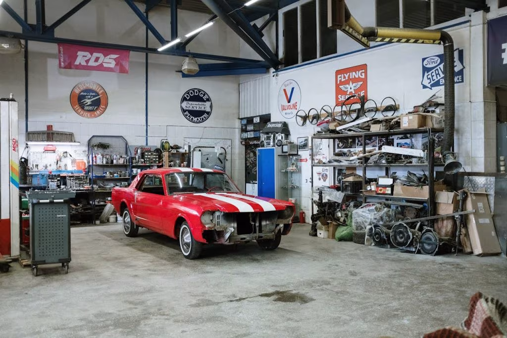 Czerwony klasyczny Mustang w trakcie renowacji w warsztacie samochodowym pełnym części i narzędzi