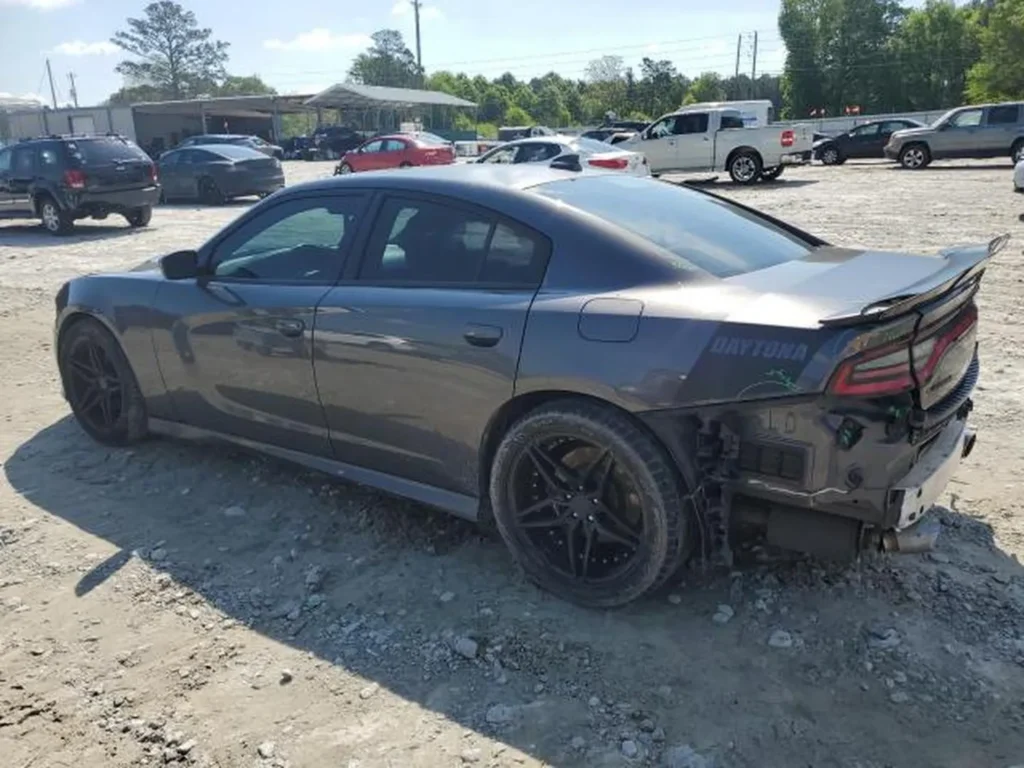 Tył i bok szarego Dodge Chargera Daytona; brak tylnego zderzaka, widoczne uszkodzenia po kolizji.