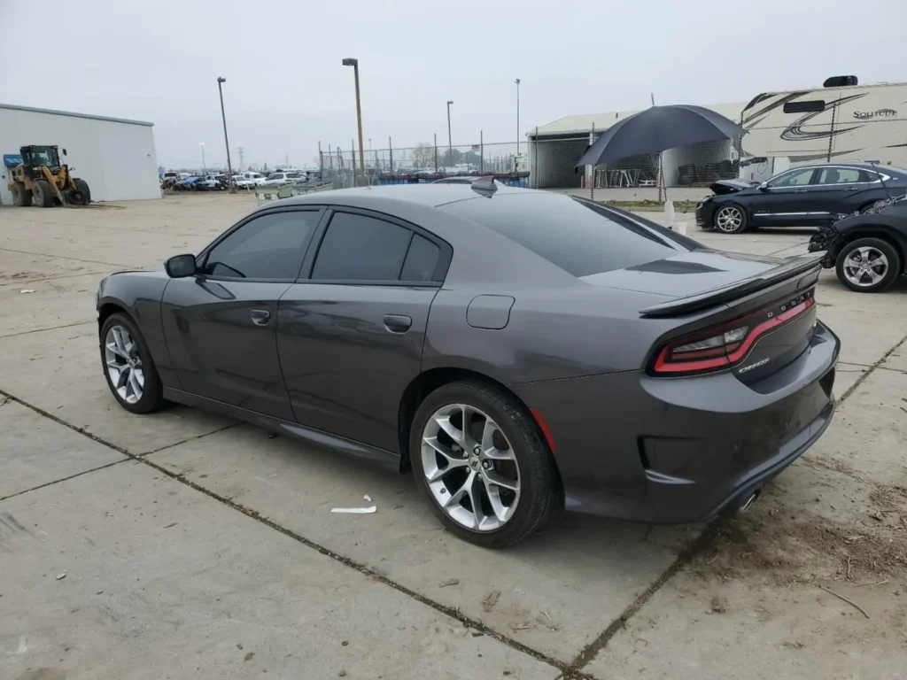 Szary Dodge Charger sedan z przyciemnianymi szybami, widok z tyłu z lewej strony na betonowym placu.