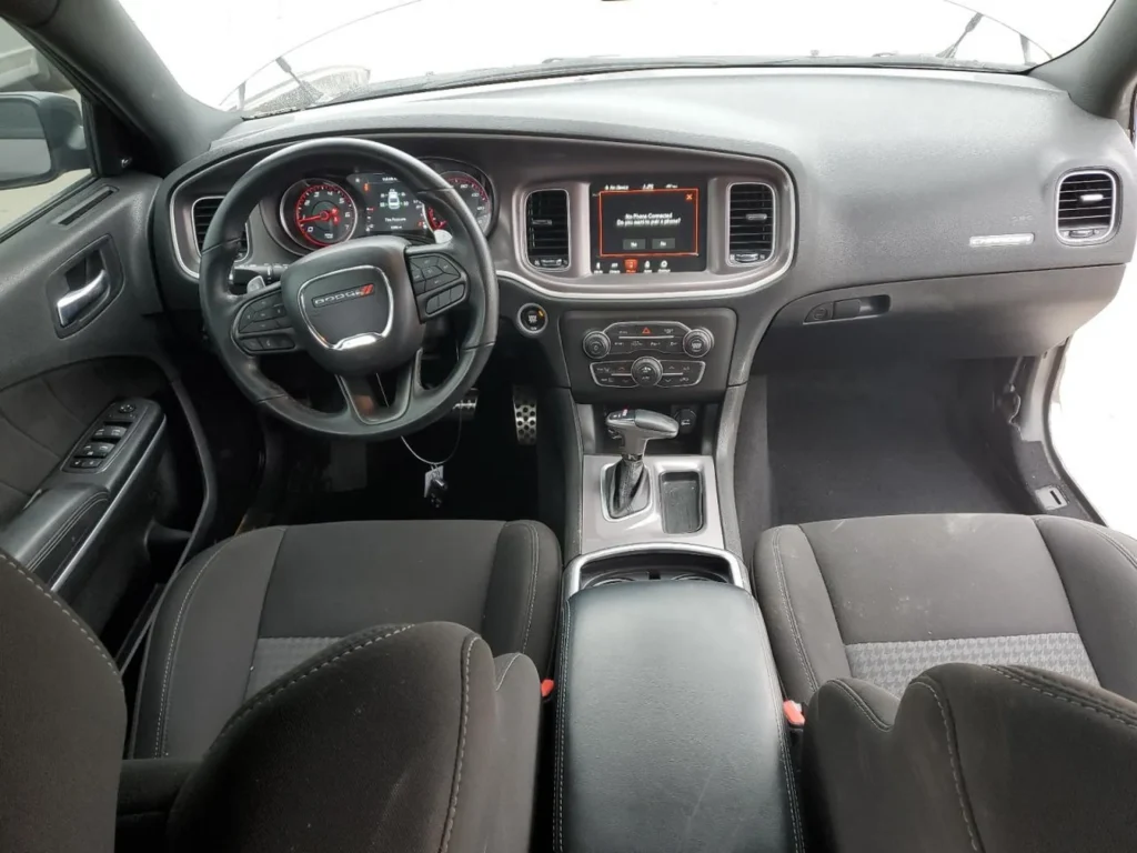 Wnętrze Dodge’a Chargera z czarną tapicerką, widok na kokpit, kierownicę i konsolę środkową.