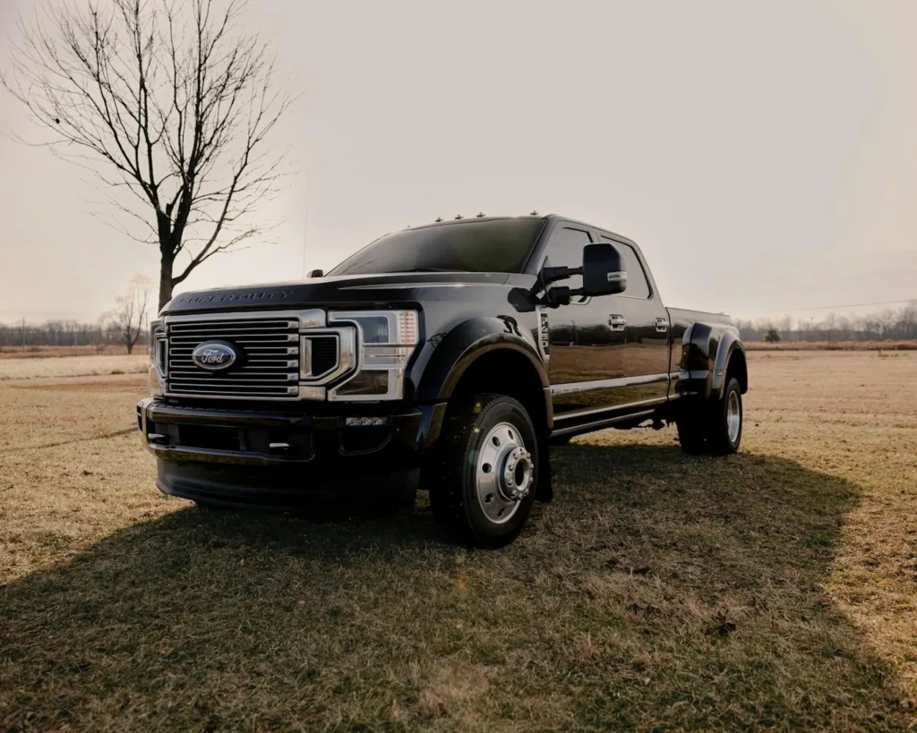 Czarny Ford F-450 Super Duty zaparkowany na otwartym polu, z potężnym grillem i masywną sylwetką pickupa.