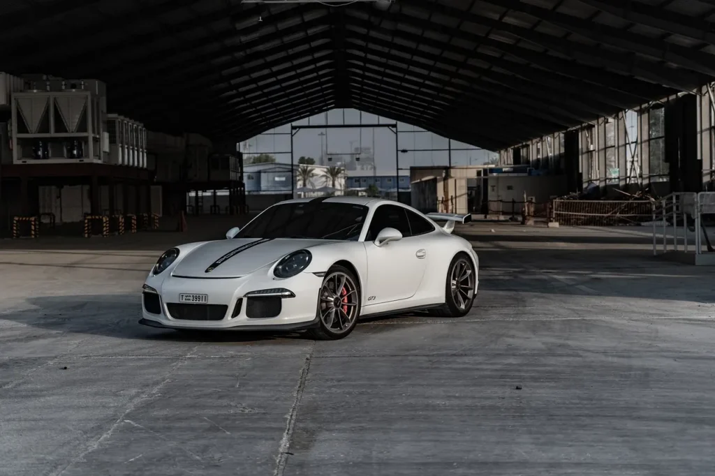 Białe Porsche 911 GT3 zaparkowane w opuszczonym magazynie, z agresywnym designem i sportowym charakterem.