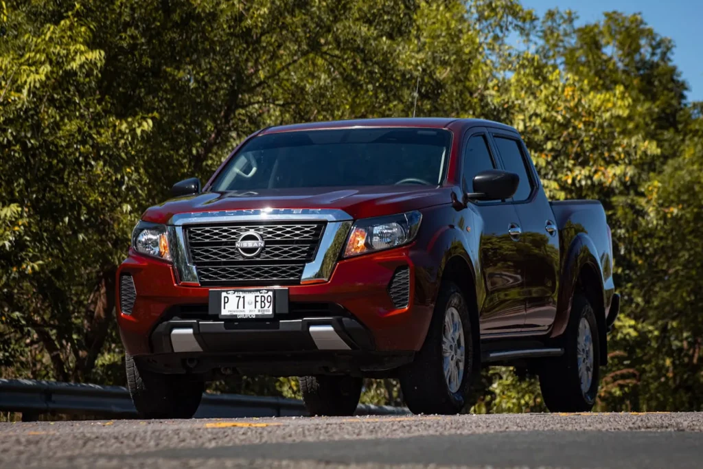 Czerwony pick-up Nissan Frontier z USA w wersji amerykańskiej – solidny i niezawodny samochód do pracy i codziennego użytku.