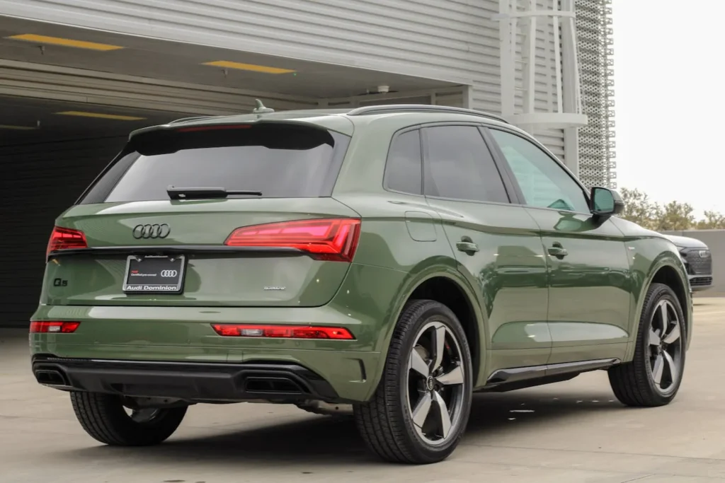 Tylna i boczna część zielonego Audi Q5 z napędem quattro, zaparkowanego przed salonem samochodowym