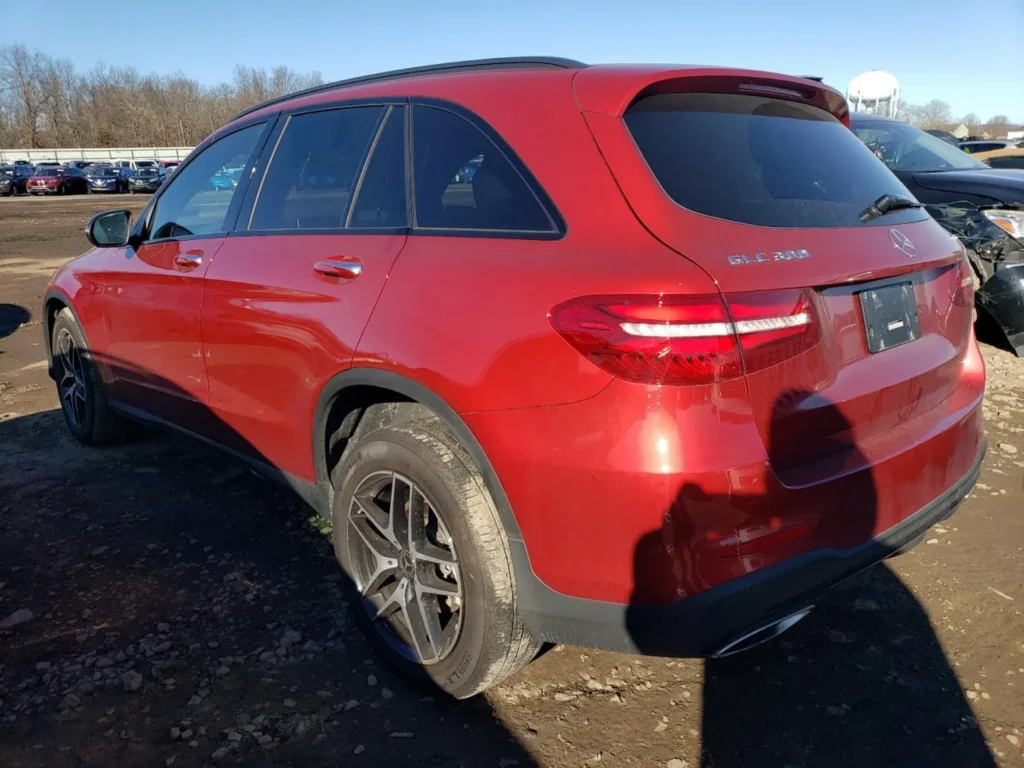 Tył i lewy bok czerwonego GLC 300 4MATIC; czarne listwy, relingi dachowe, brak tablicy, lakier zachowany.