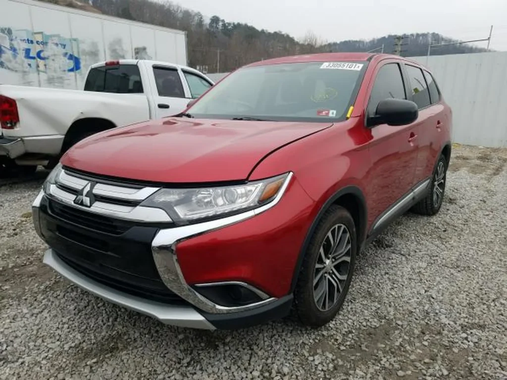 Czerwony Mitsubishi Outlander, widok z przodu-prawego narożnika, maska lekko uniesiona.