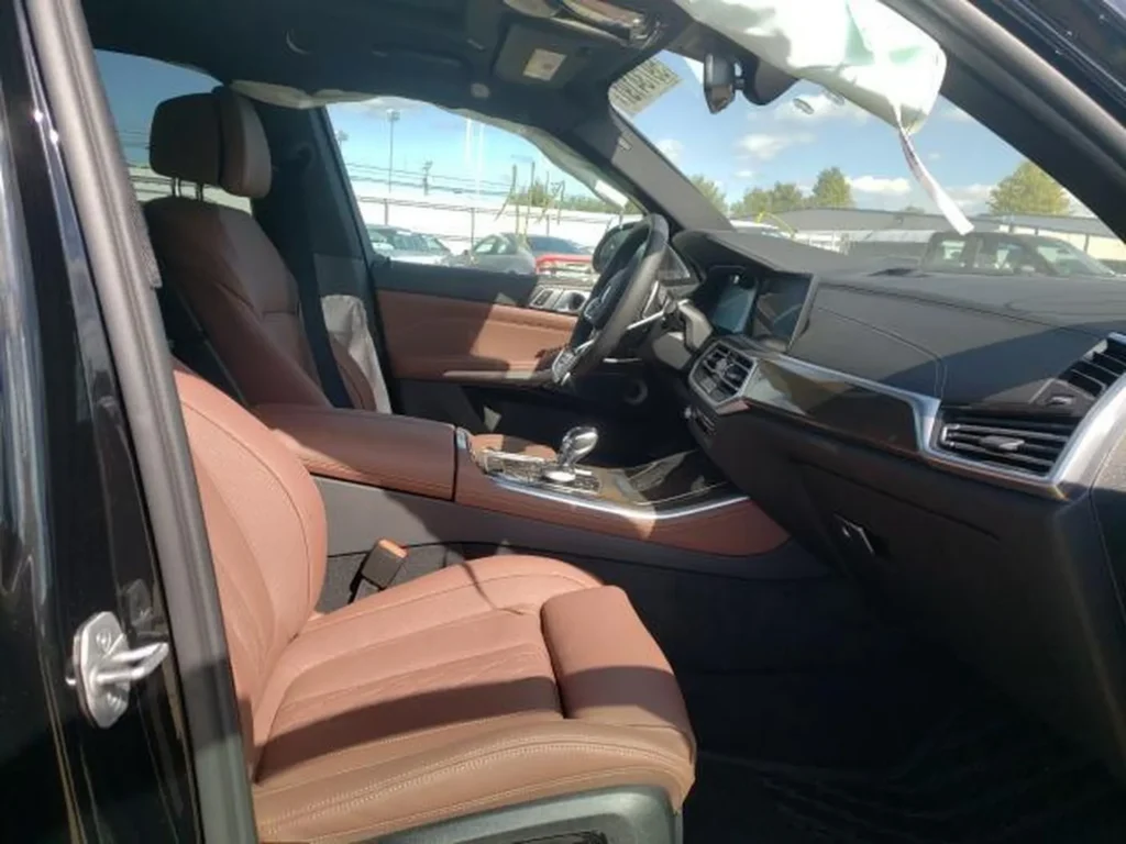 Wnętrze BMW X5, brązowe fotele, kokpit, rozwinięta poduszka kurtynowa przy dachu.