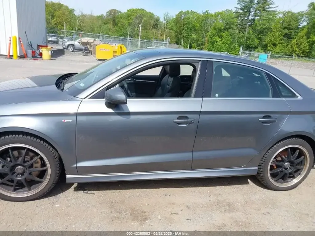 Srebrny Audi A3 sedan - widok z boku na parkingu żwirowym.