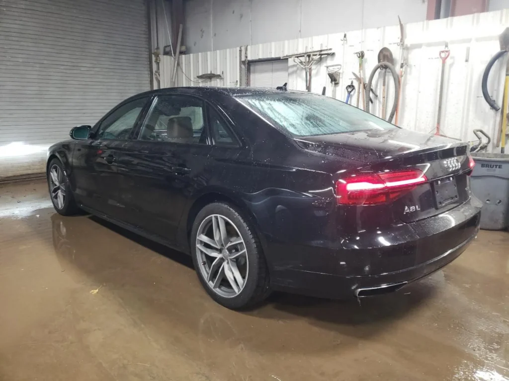 Czarny Audi A8L - widok z tyłu i boku w hali warsztatowej.