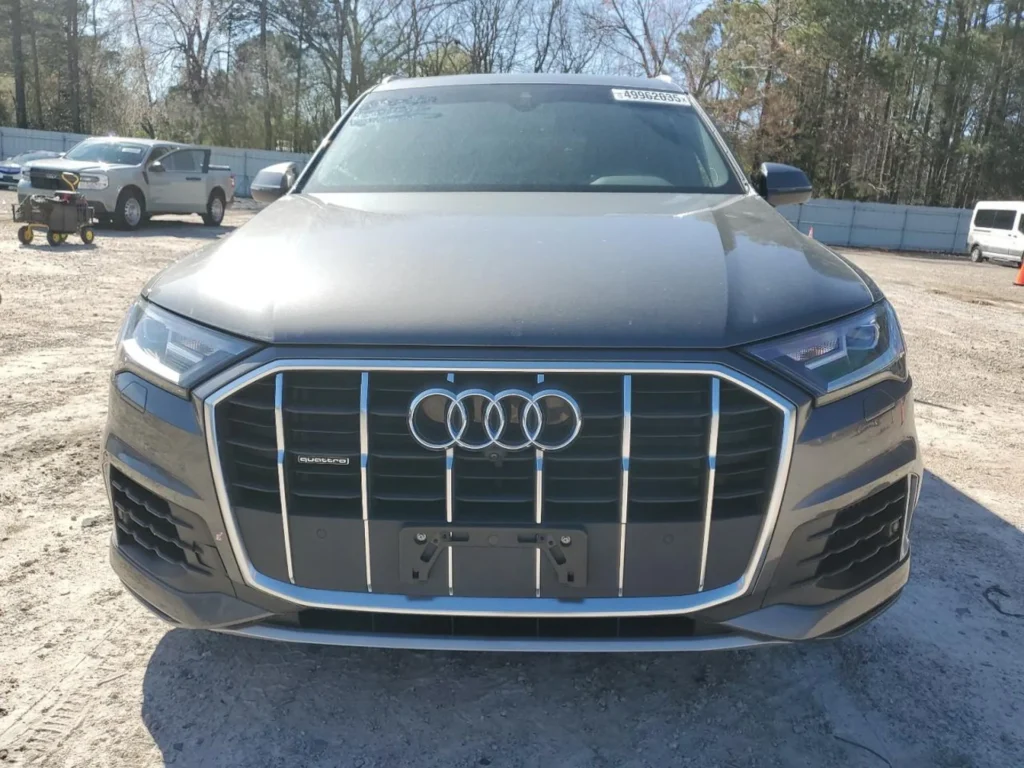 Przód szarego Audi Q7 z charakterystycznym grillem singleframe na żwirowym placu