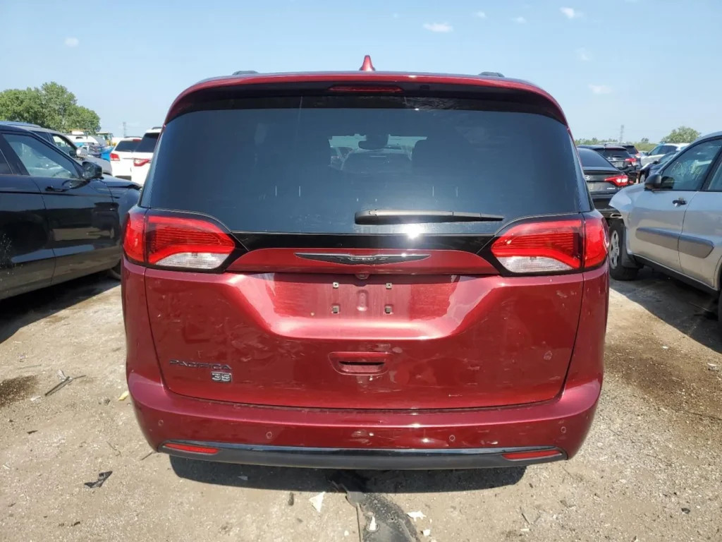 Czerwony Chrysler Pacifica sfotografowany od tyłu na zatłoczonym parkingu.