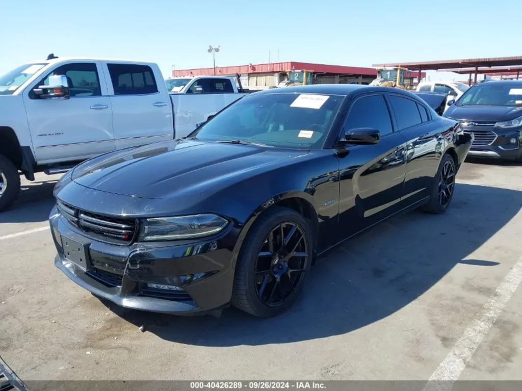 Czarny Dodge Charger sedan z czarnymi felgami, ujęcie z prawego przodu na placu aukcyjnym.
