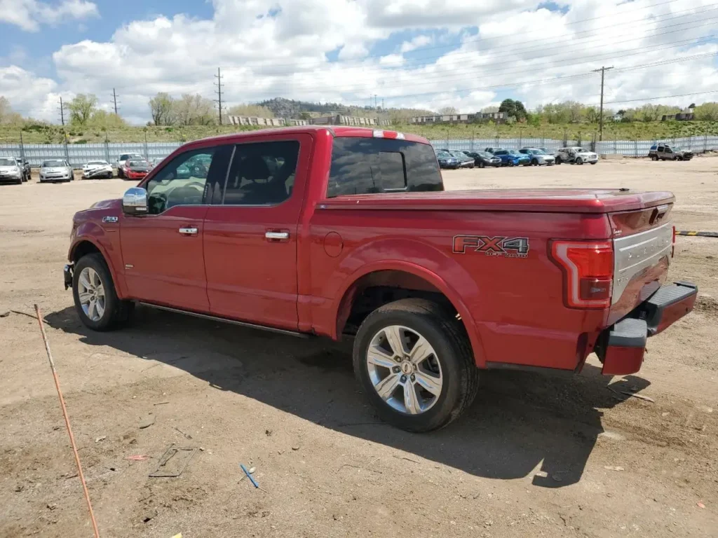 Tył czerwonego Forda F-150 FX4 Off Road z podwójną kabiną i zabudowaną przestrzenią ładunkową, zaparkowanego na piaszczystym placu.