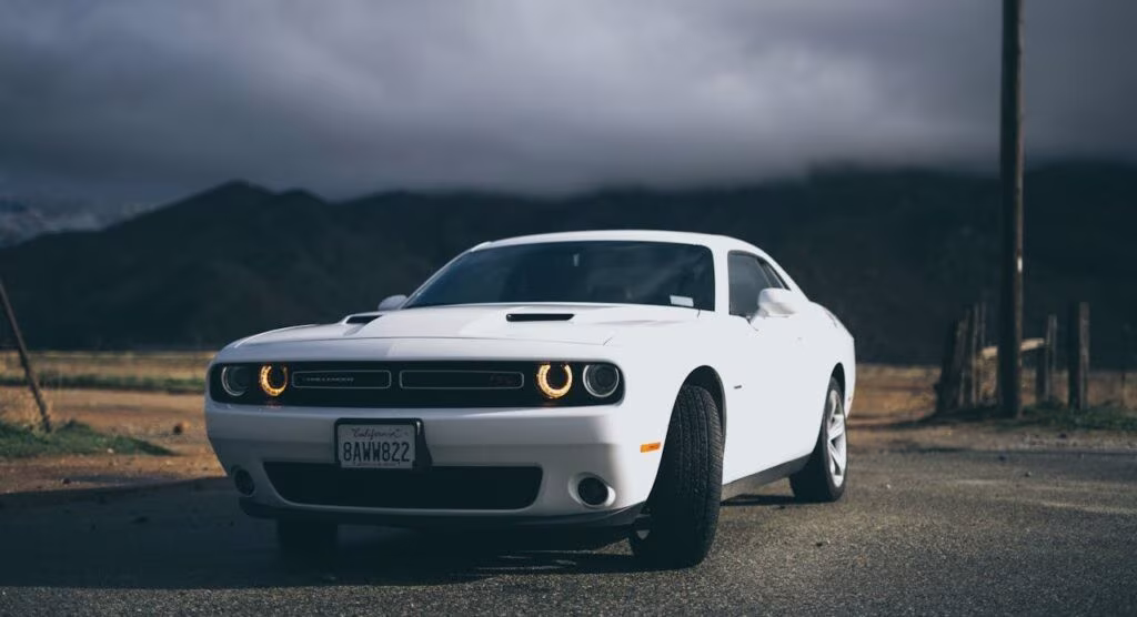 Biały Dodge Challenger na tle gór pod pochmurnym niebem